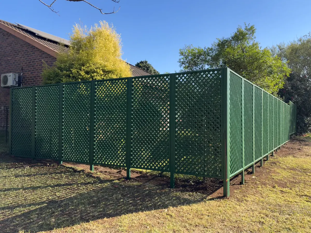 A completed custom green lattice trellis screen enclosing a garden in Howick.