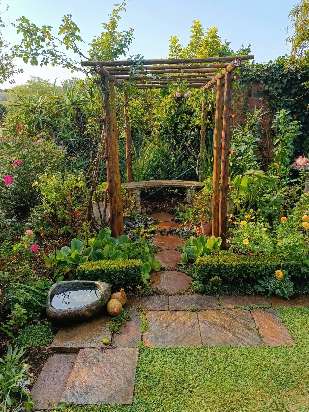 Detailed garden design featuring a custom rustic timber pergola, a stone garden bench, and a natural stone paver walkway.